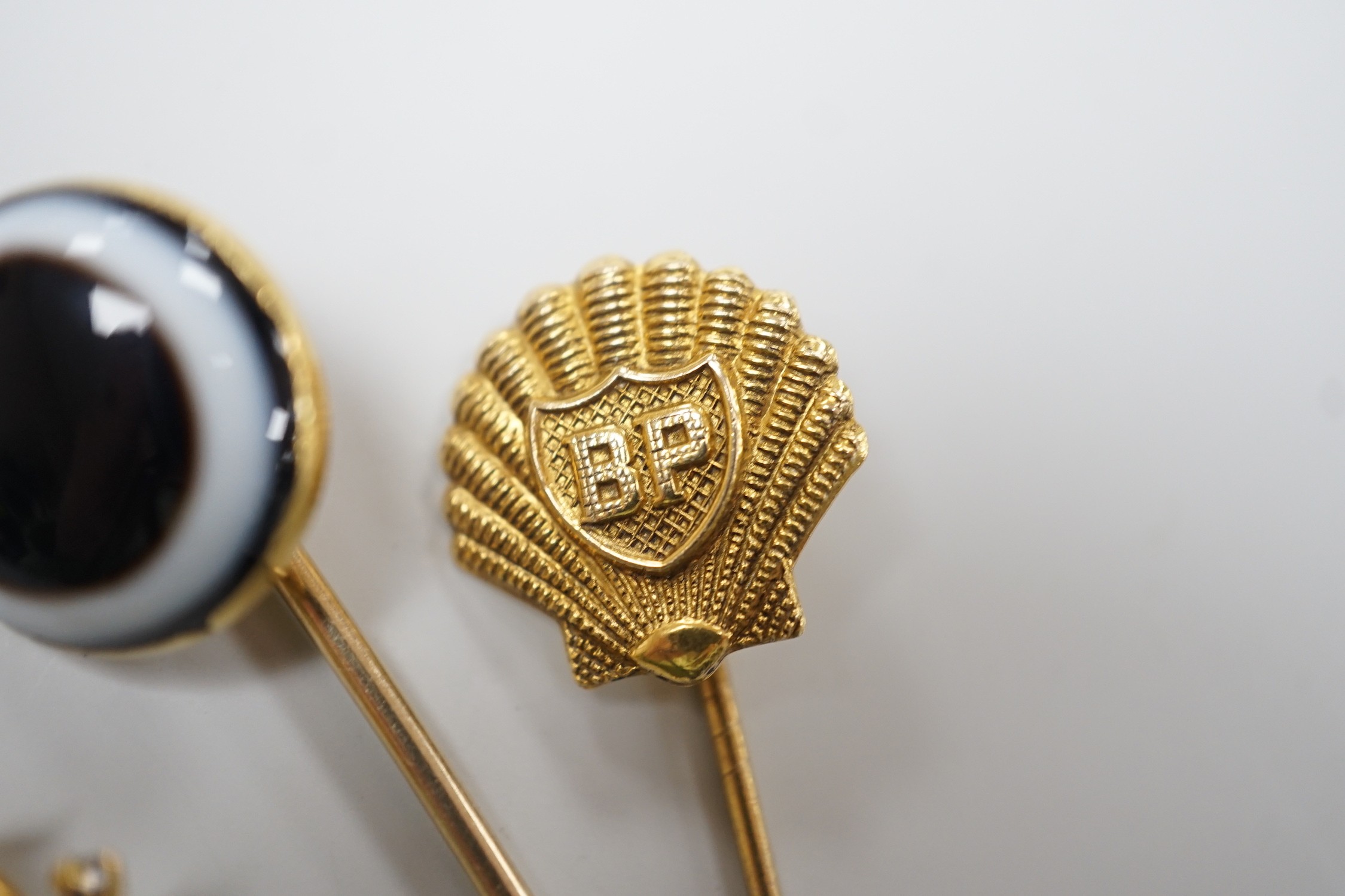 A Victorian yellow metal and banded agate set stick pin, 84mm, a yellow metal Royal Warwickshire Regt. stick pin and a 1970's 9ct gold BP stick pin, gross weight 11.5 grams.